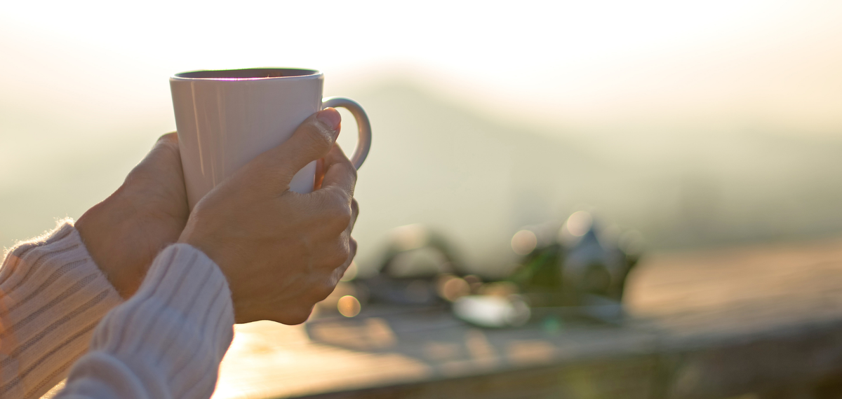 Hands holding coffee cup on a sunny day