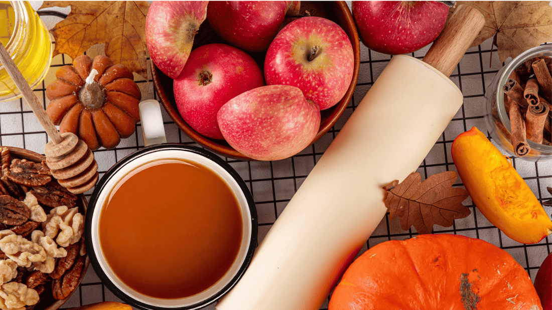 Cup of coffee surrounded by nuts, apples, pumpkin, cinnamon, leaves and other fall ingredients